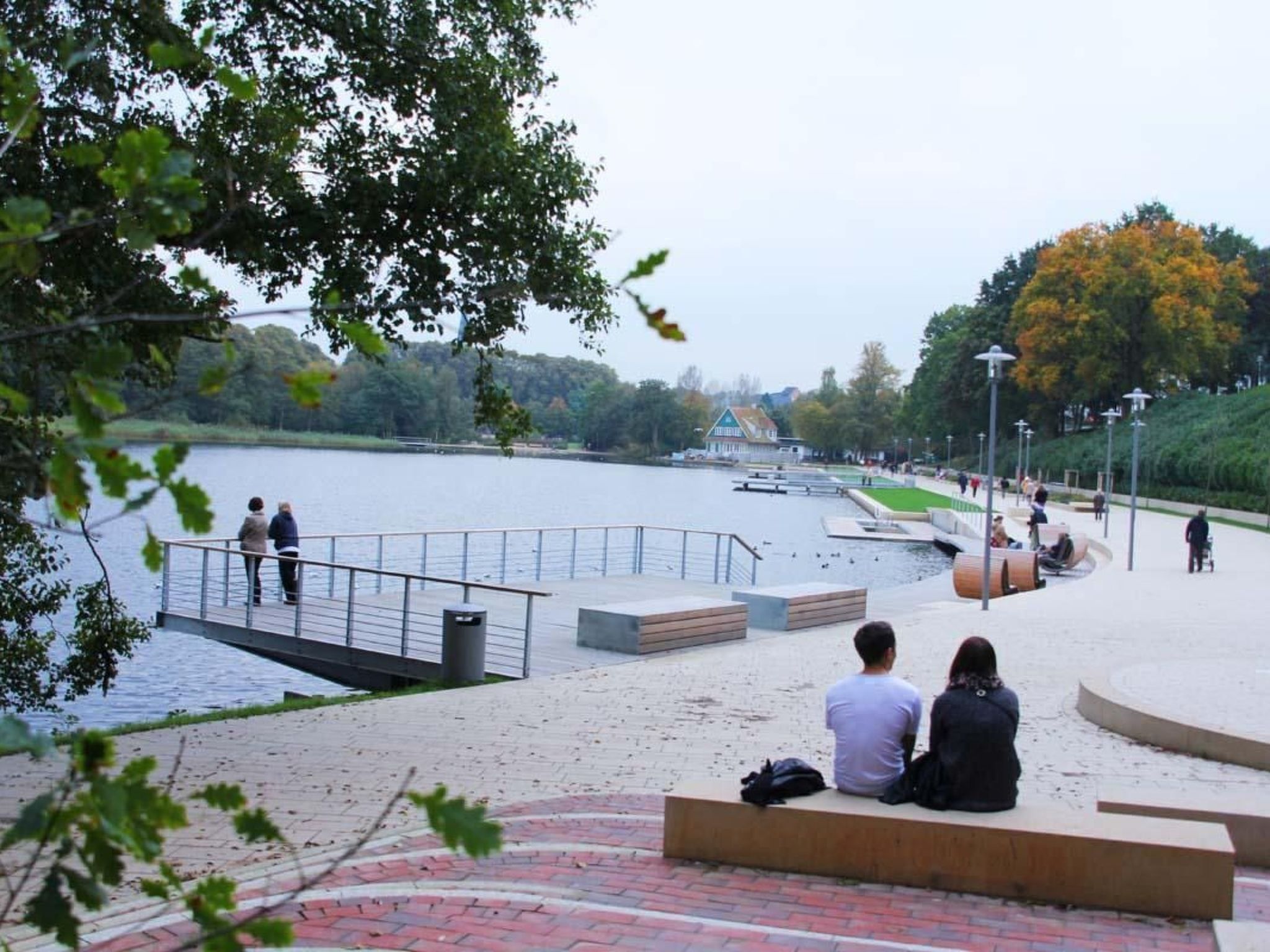 A riverside park with a viewing platform, benches, and a small bridge.