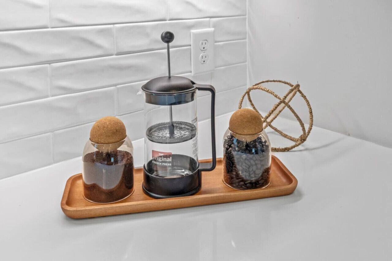 Eine Kaffeemaschine auf einem Holztablett mit zwei Gläsern mit Kaffeebohnen.