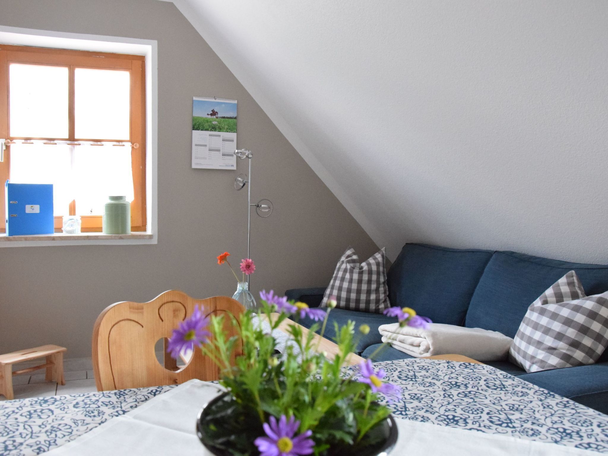 Habitació acollidora amb un llit, una finestra, un escriptori i un sofà blau.