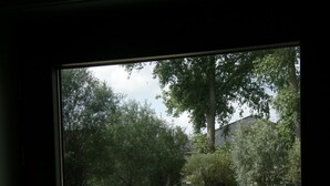 En terrasse med bord og stole, en dam og træer.