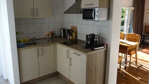 Eine kleine Küche mit weißen Schränken, einer Mikrowelle und einer Kaffeemaschine.