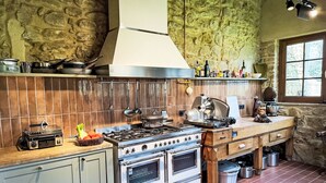 Een keuken met een fornuis, oven en diverse kookgerei.