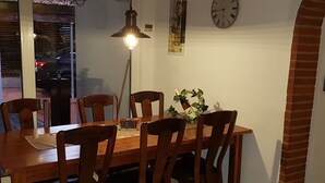 En matplats med ett träbord och stolar, en hänglampa, en klocka och en liten prydnadsväxt.