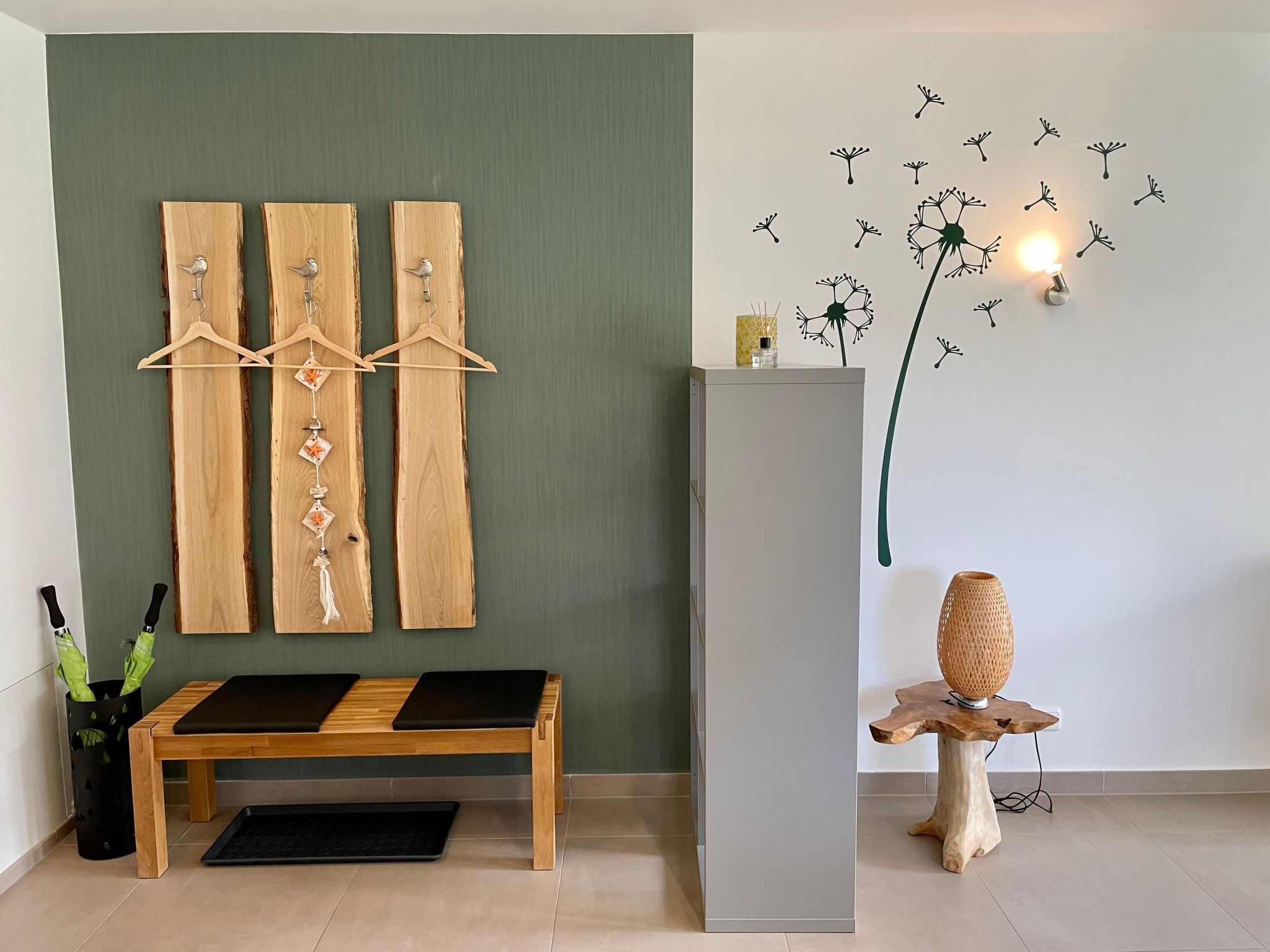 A room with a wooden bench, a grey cabinet, and a wall with a dandelion decoration.