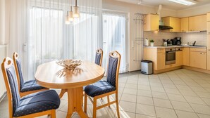 Moderni keittiö, jossa on puiset kaapit, sisäänrakennettu uuni ja kahvinkeitin.