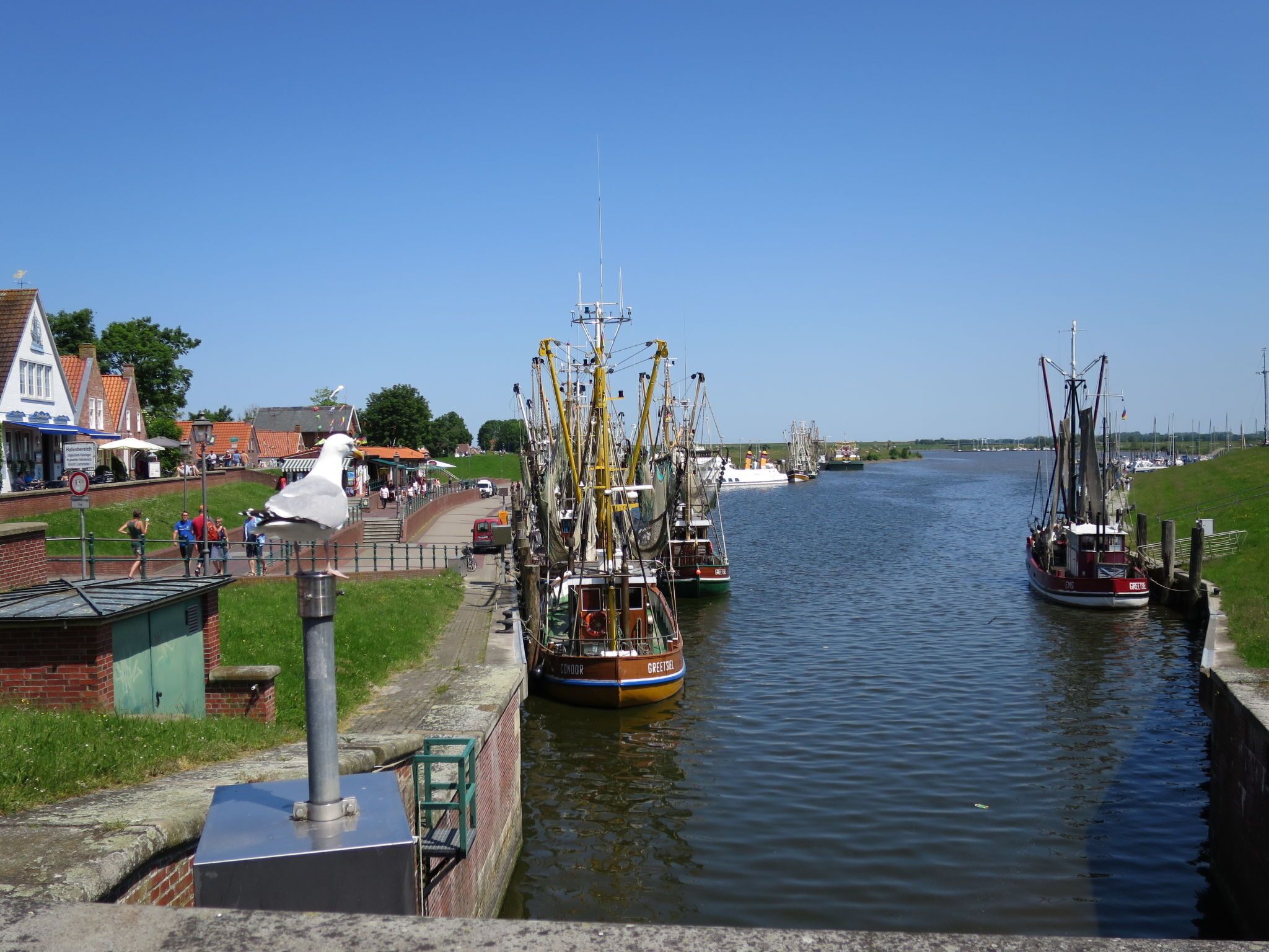 Un canal bordé de quais où sont amarrés des bateaux, une promenade piétonne et des bâtiments à l’architecture traditionnelle.