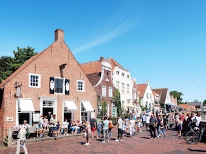 Eine historische Straße mit traditionellen Backsteingebäuden, Kopfsteinpflaster und einer Menschenmenge.