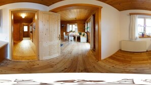 A wooden interior with a dining area, kitchen, and a large open space.