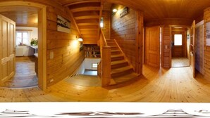 A wooden interior with a spiral staircase, wooden walls, and a small kitchen area.