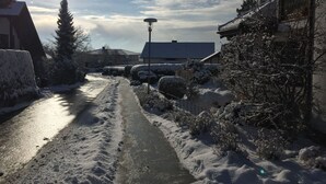 Ein verschneiter Weg, der zu einem Gebäude mit einem geneigten Dach führt.