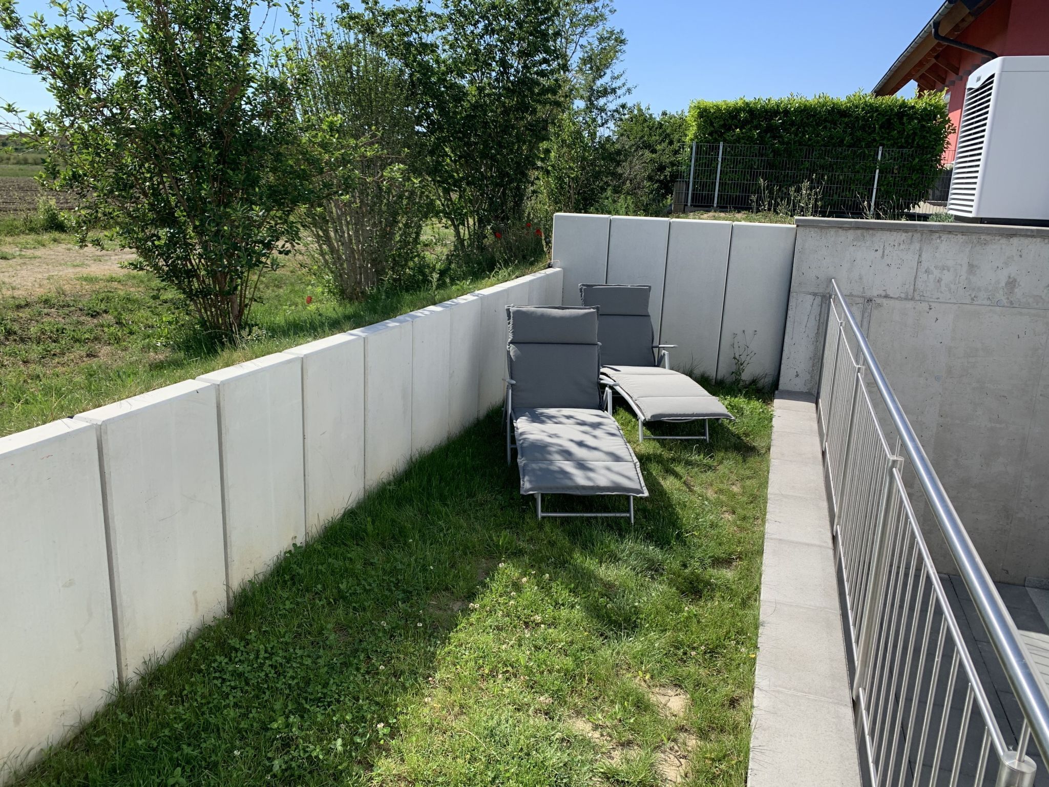 Un'area patio con due poltrone e un muro in cemento.