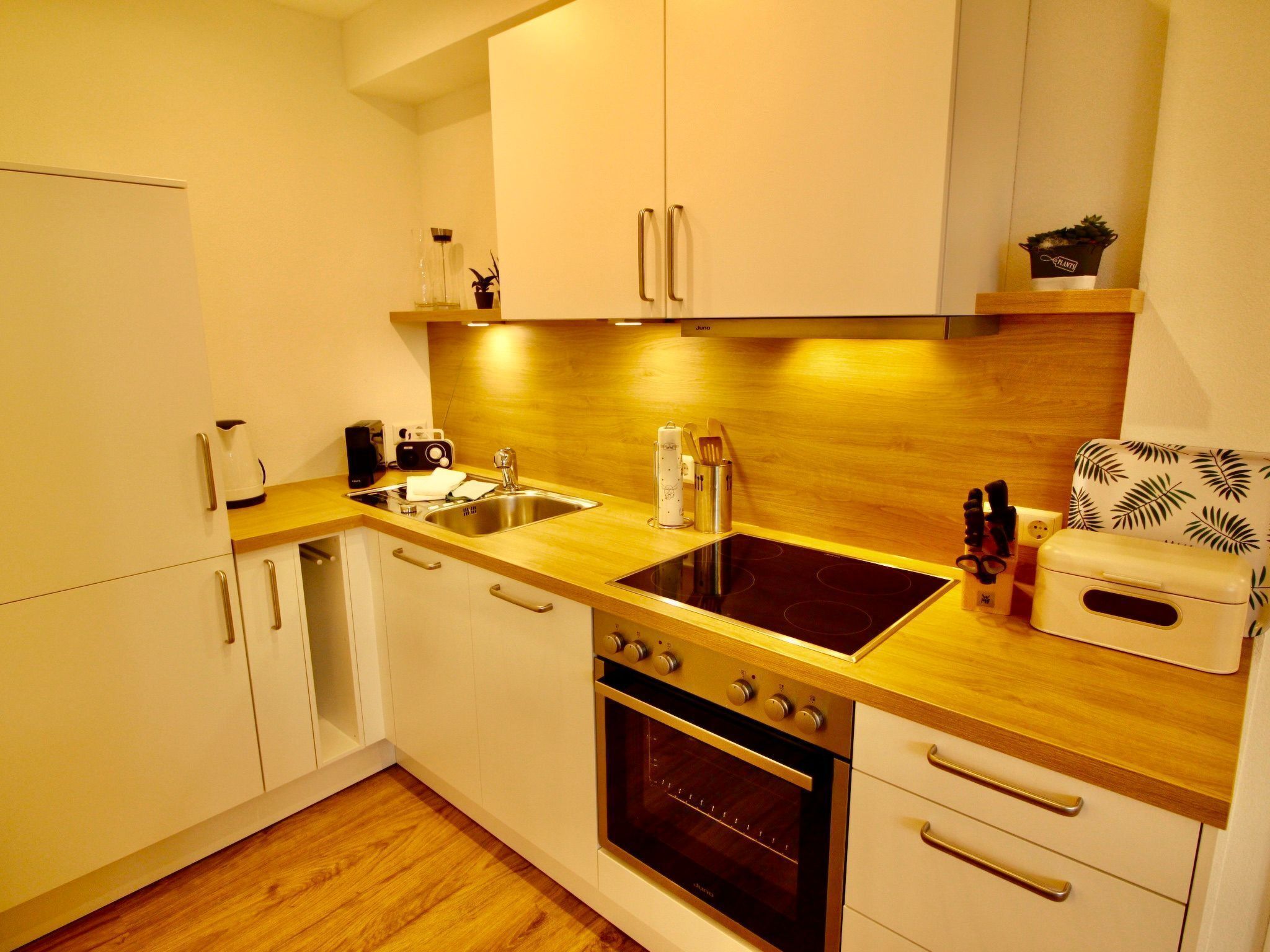 A modern kitchen with white cabinets, a wooden countertop, a built-in oven, and a sink.