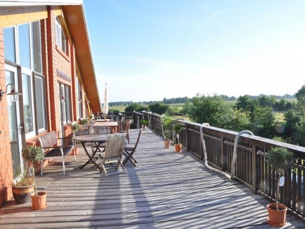 Eine Holzterrasse mit Sitzgelegenheiten und Blumentöpfen.