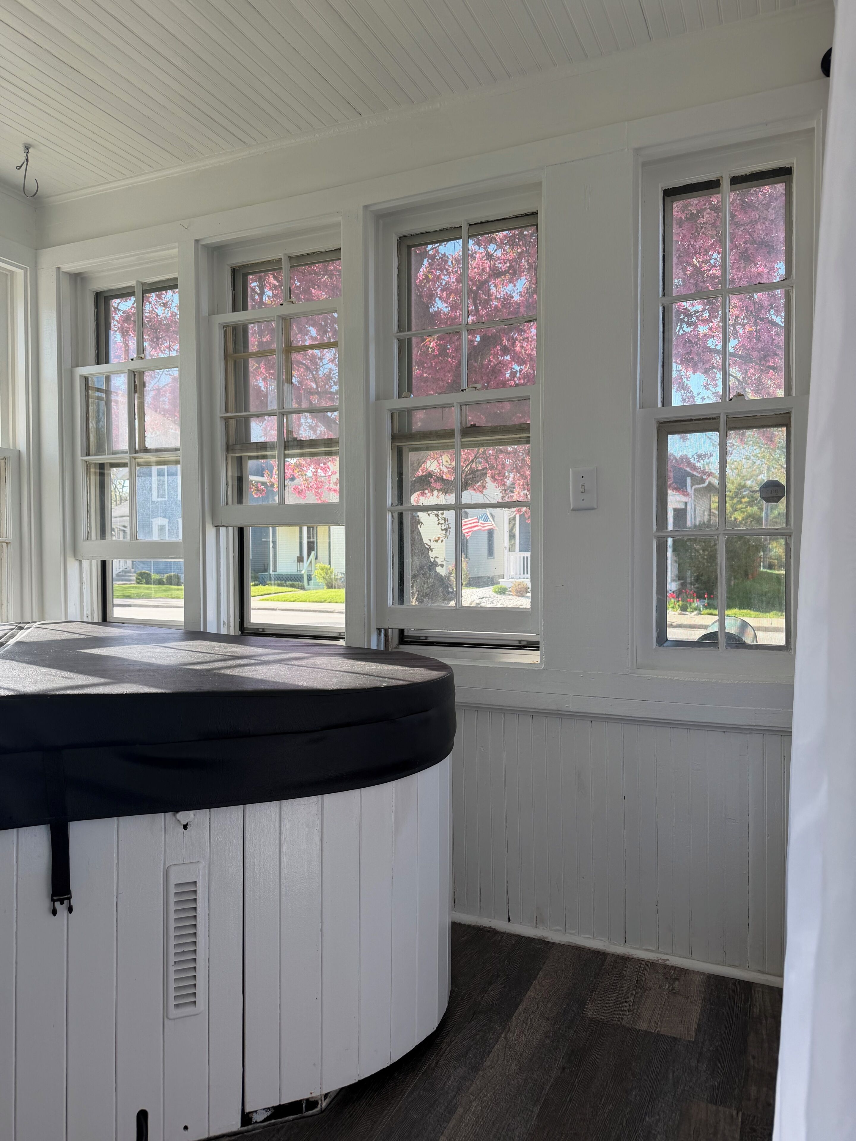 A room with a hot tub, large windows, and a view of a neighborhood.