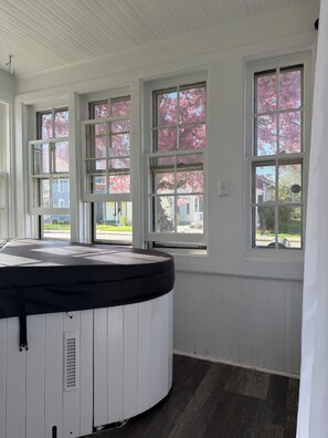 Ein Zimmer mit Whirlpool, großen Fenstern und Blick auf eine Wohngegend.