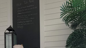 Et spa-område med et boblebad, en tavle med regler, en dekorativ lanterne og en plante.