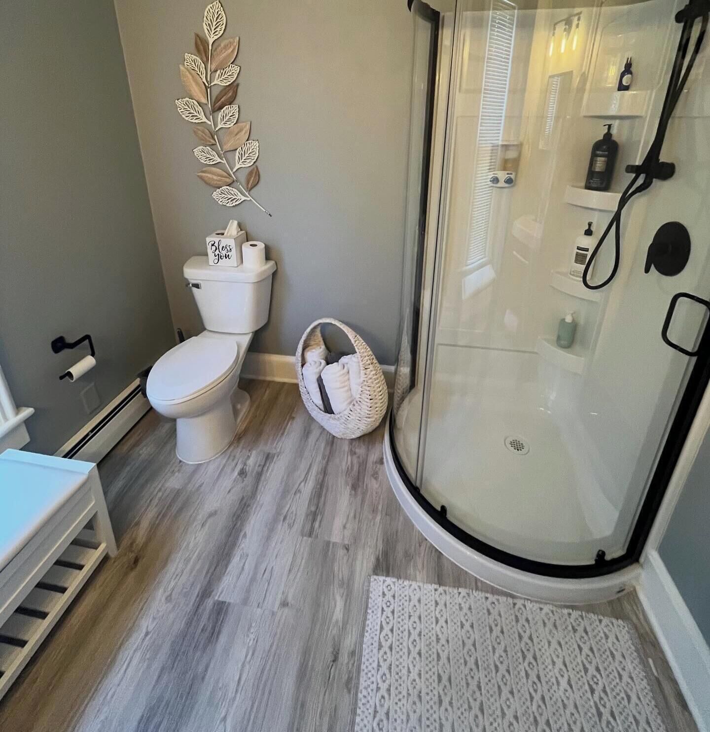 A bathroom with a toilet, a shower, and a small white basket.