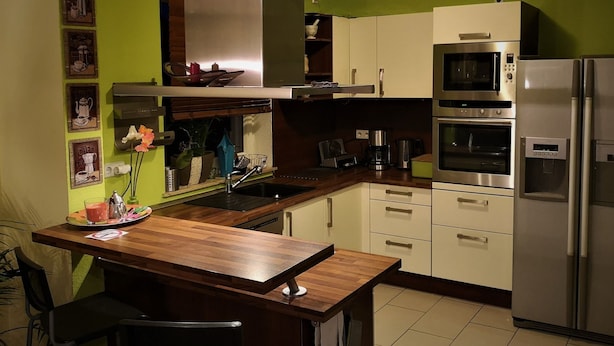 Une cuisine moderne avec un îlot central en bois, des appareils électroménagers en acier inoxydable et des murs verts.