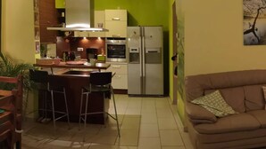 Une cuisine dotée d’un îlot central, d’un réfrigérateur et d’un coin repas avec un canapé et des chaises.