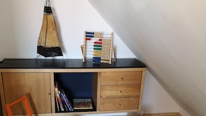 Une pièce avec un bureau, une petite voiture jouet verte, deux tabourets verts et un sol à carreaux noirs et blancs.