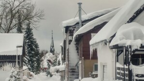 Eine verschneite Straße mit Häusern und einem Kirchturm.