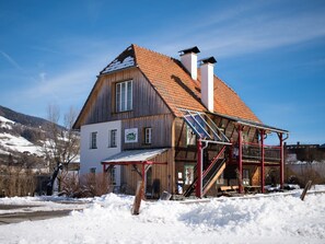 Ein Holzhaus mit geneigtem Dach, Solaranlagen und einer Treppe, die zum Eingang führt.
