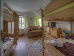 Une pièce en bois avec des lits superposés, un canapé, une télévision et un tableau accroché au mur.