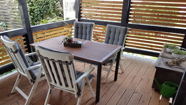 Une terrasse en bois avec une table et des chaises, entourée d’une clôture en bois.