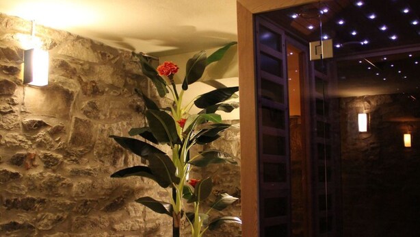Een stenen muur met een bloempot en een houten bankje.