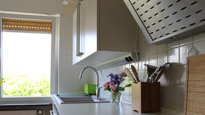 Een moderne keuken met een wit aanrecht, een roestvrijstalen spoelbak en een houten messenhouder.