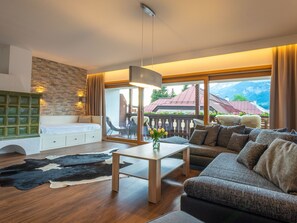 Ein modernes Wohnzimmer mit einer Couch, einem Couchtisch und Bergblick durch große Fenster.