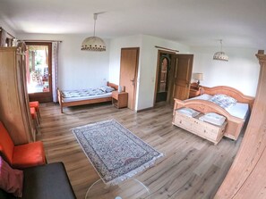 Una habitación con dos camas de madera, un armario de madera, una mesita pequeña, una silla y un tapete estampado.