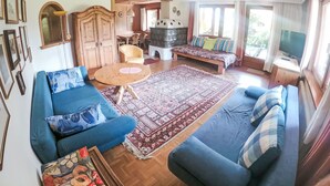 A spacious living area with a sofa set, a coffee table, a fireplace, and a television.