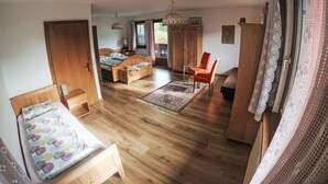A bedroom with a wooden bed, a small table, and a chair. There is a wardrobe, a window with curtains, and a door. - Haus Fink - Igls by Interhome (Innsbruck)