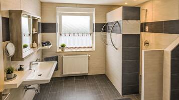 Un baño moderno con lavamanos, espejo, toallero y ventana con cortina.