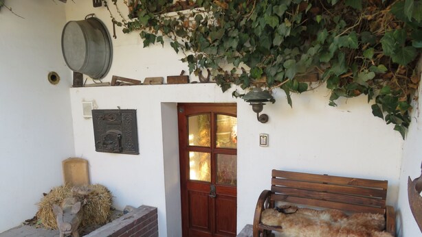 A rustic entrance with a wooden bench, a metal barrel, and a brick wall. - Apartment Kontor by Interhome (Marschacht)