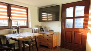 A cozy room with a wooden table, a chair, a wooden dresser, a television mounted on the wall, and a wooden door. - Apartment Kontor by Interhome (Marschacht)