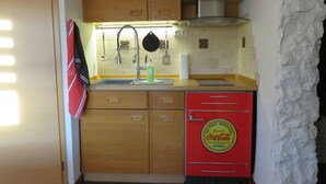 A compact kitchen with wooden cabinets, a microwave, and a red Coca-Cola refrigerator. - Apartment Kontor by Interhome (Marschacht)