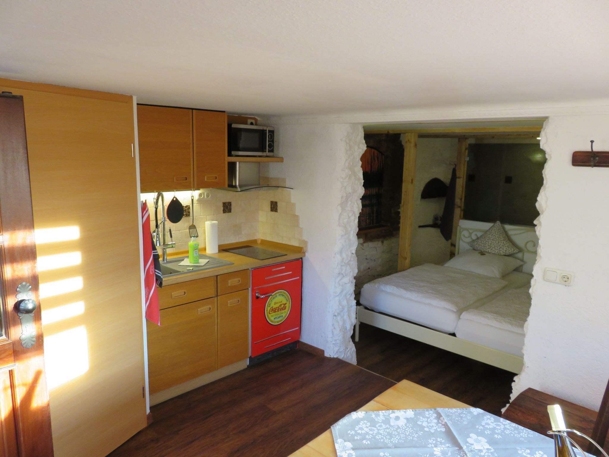 A compact room with a kitchenette, a bed, and a small table.