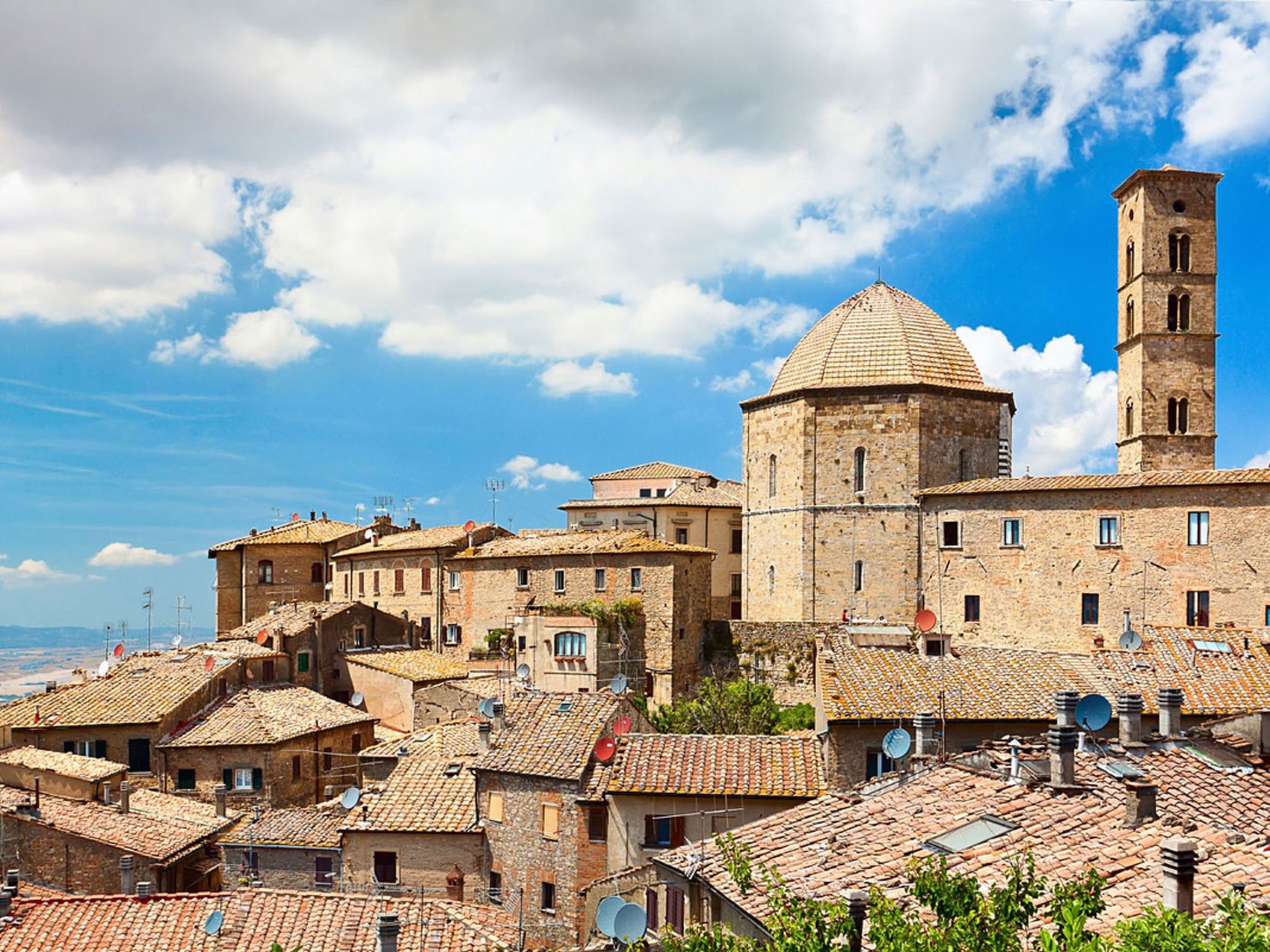 A historic town with stone buildings, a prominent church with a dome, and a bell tower.