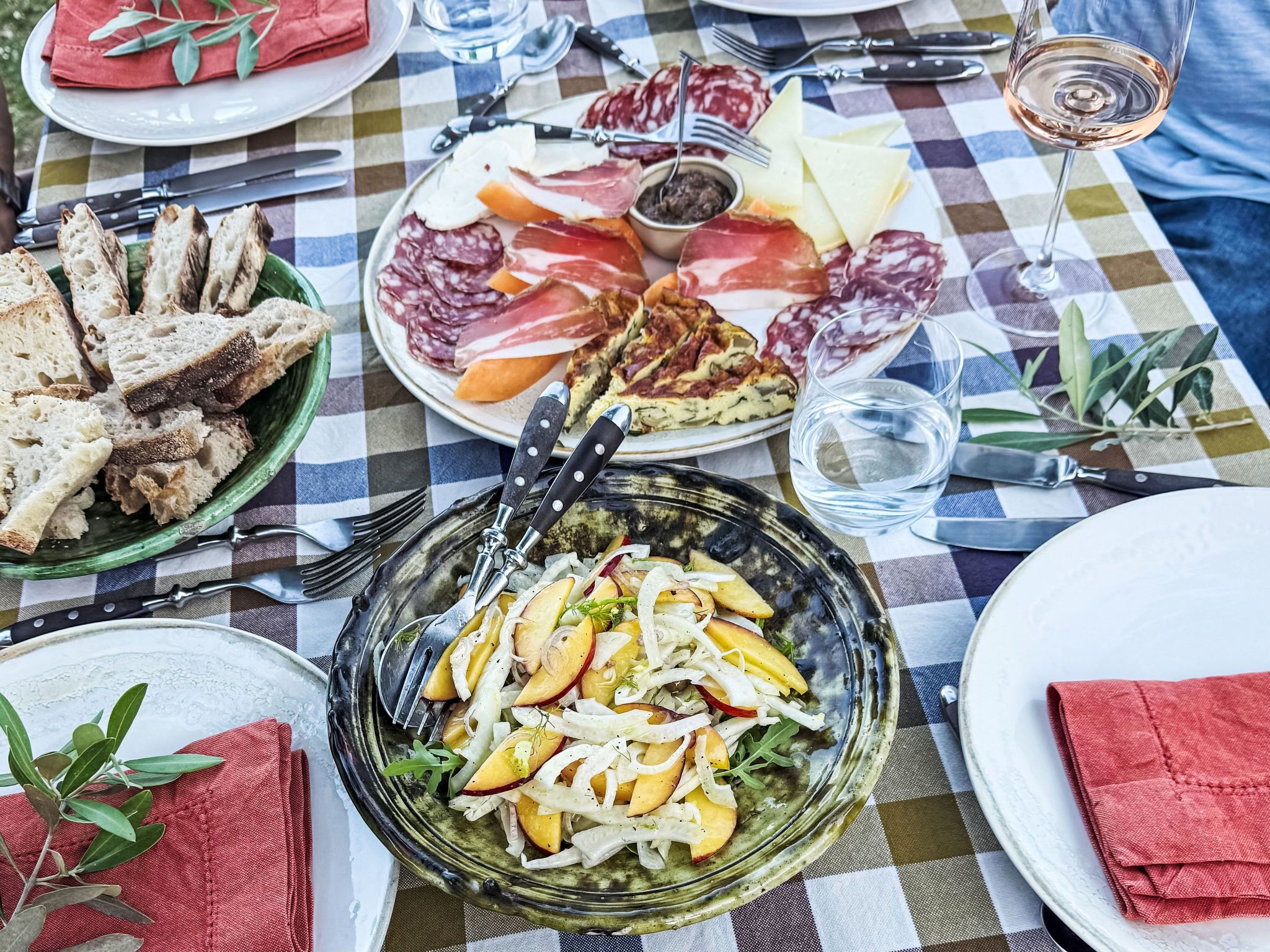 Una mesa servida con diversos alimentos, como pan, queso, embutidos y una ensalada.