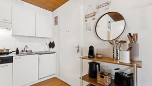 Uma cozinha moderna com armários brancos, teto de madeira, cafeteira, torradeira e um espelho na parede.