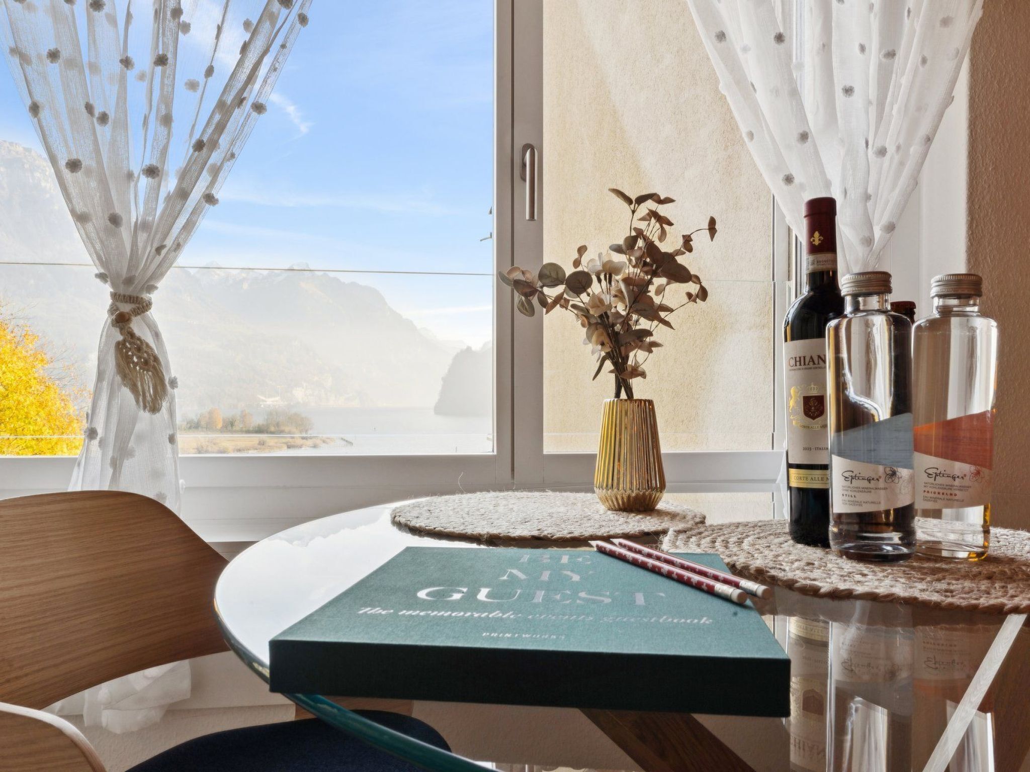Et bord med en bog med titlen "The Guest Book" og tre flasker vin.