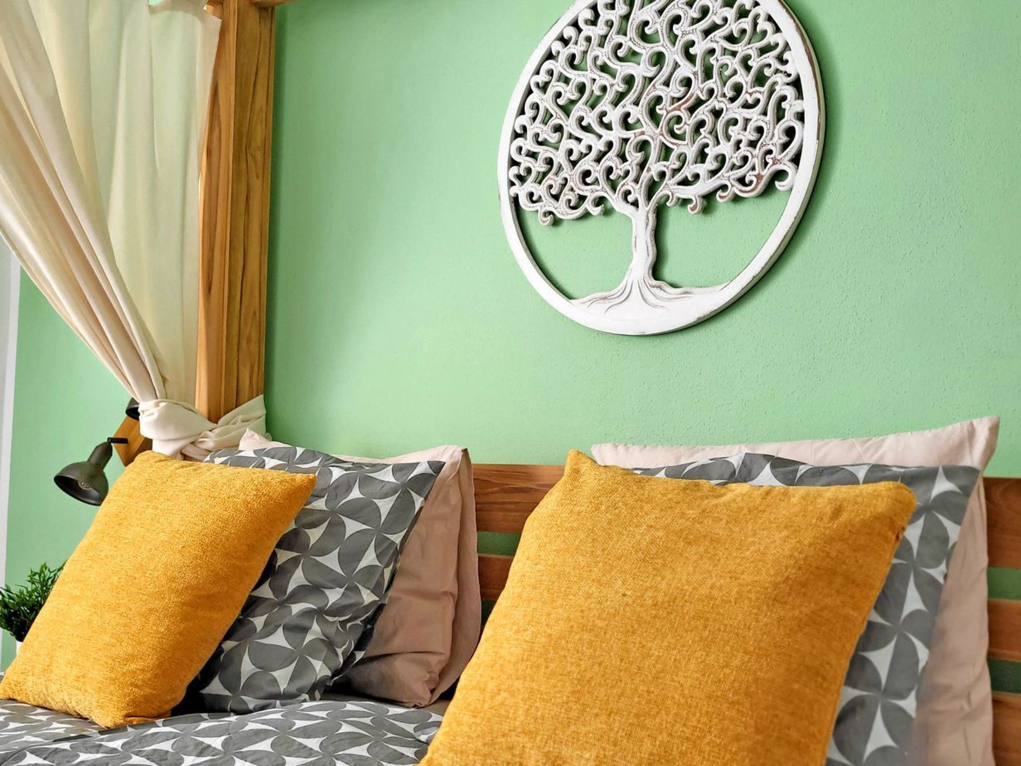 A bed with patterned pillows and a decorative tree wall hanging.