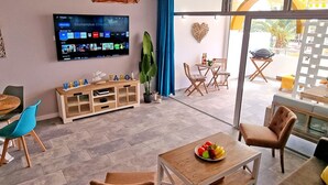 A modern living room with a flat-screen TV, wooden furniture, and a view to the outside. - Vista Faro by Interhome (Morro Jable)