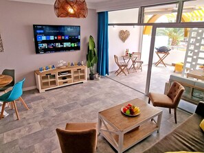 Ein modernes Wohnzimmer mit Flachbildfernseher, Holzmöbeln und Blick ins Freie.