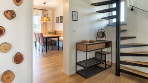 A modern interior with a spiral staircase, a dining area, and a wall decorated with wooden slices. - Overlook Lodge by Interhome (Vöhl)