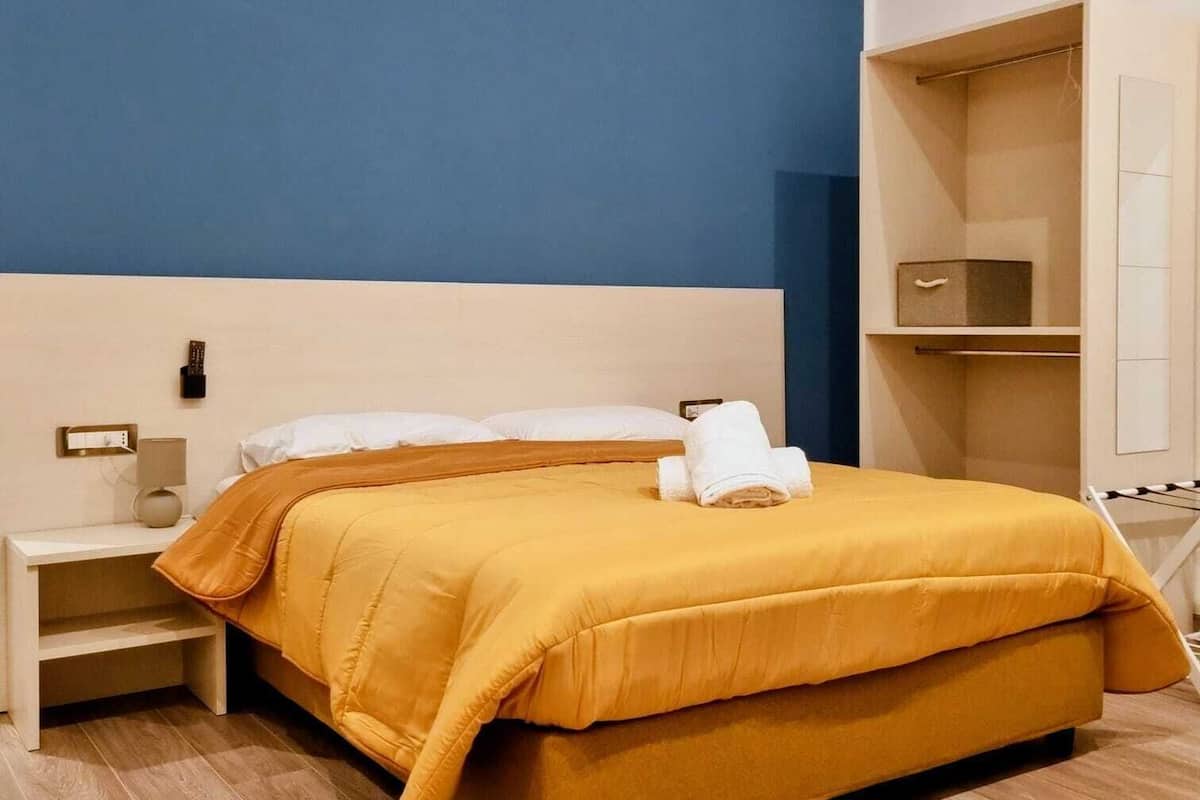 A hotel room with a bed, a nightstand, a wardrobe, and a mirror.