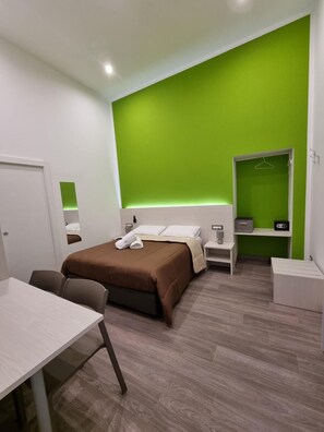 A modern hotel room with a large bed, a desk, a chair, a wardrobe, and a mirror. - Casa Maluma  (Naples)