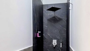 Une douche moderne avec un mur en marbre noir, une douchette à main et un panneau de commande.